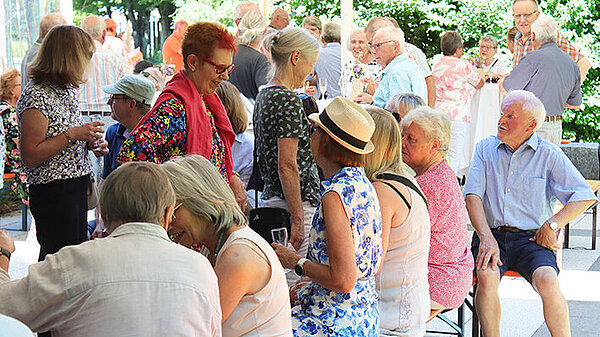 Ein große Gruppe Seniorinnen und Senioren sitzen im Freien zusammen.