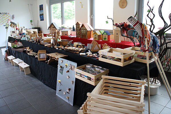 Auf einem langen Tisch sind verschiedene Holzprodukte aufgestellt.