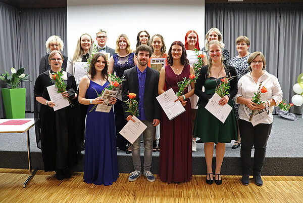 Gruppenbild mit 15 jungen Menschen. Alle halten eine Urkunde und eine Rose in der Hand.