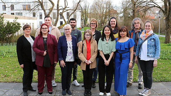 Eine Gruppe feierlich gekleideter Menschen, alle lächeln freudig.
