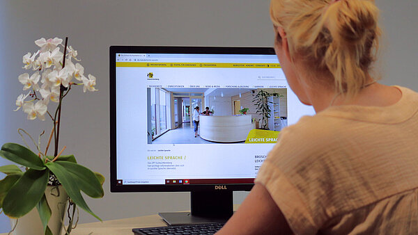 Eine Frau sitzt vor einem Bildschirm, auf dem die neue Webseite zu sehen ist.