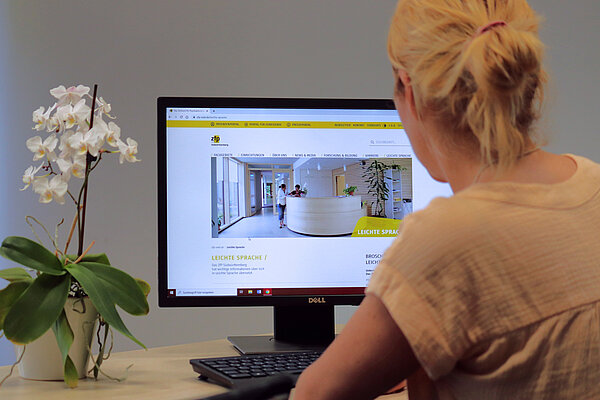 Eine Frau sitzt vor einem Bildschirm, auf dem die neue Webseite zu sehen ist.