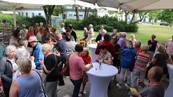 Senior:innen stehten im Garten und unterhalten sich