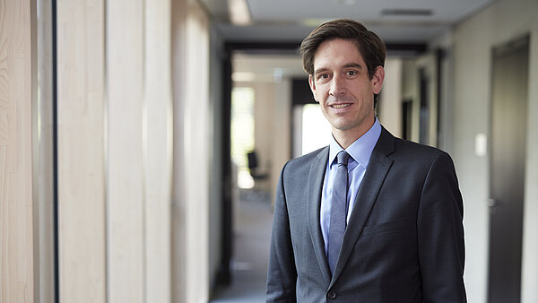 ein Mann mit dunklem Anzug und Krawatte steht im Flur