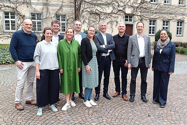 Gruppenfoto mit in die Kamera lächelnden Frauen und Männern im Innenhof eines historischen Gebäudes.