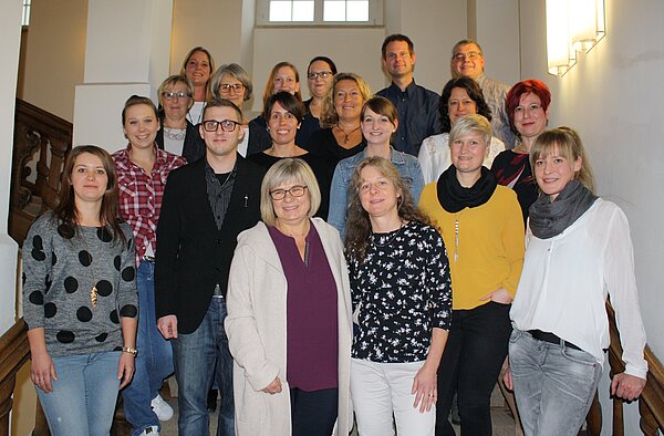 Viele Menschen sind auf einer Treppe aufgereiht und lächeln in die Kamera