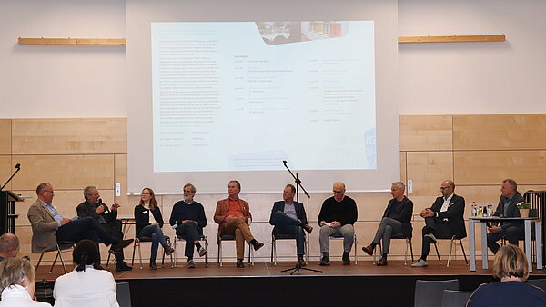 Eine Gruppe Menschen sitzt auf einer Bühne. 