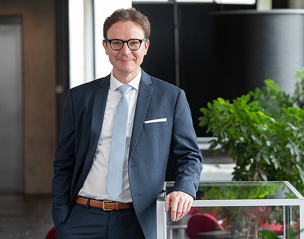 Ein freundlich aussehender Mann im mittleren Alter mit Brille im blauen Anzug