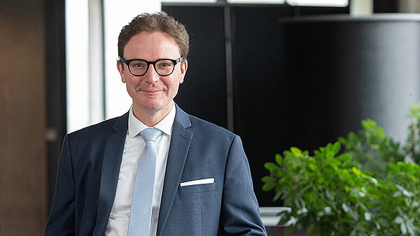 Ein freundlich aussehender Mann im mittleren Alter mit Brille im blauen Anzug