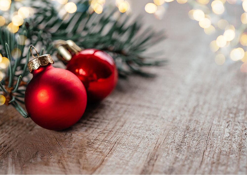 Adventsgesteck mit zwei roten Christbaumkugeln.
