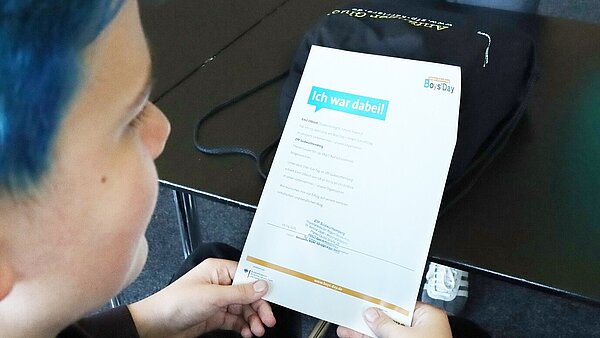 Ein Junge hält eine Urkunde in den Händen. Darauf steht "ich war dabei".