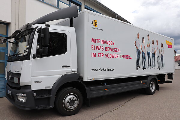 weißer LKW Beklebt mit ZfP Südwürttemberg Werbung. IN pink steht geschrieben" Miteinander. Etwas bewegen. Im ZfP Südwürttemberg.