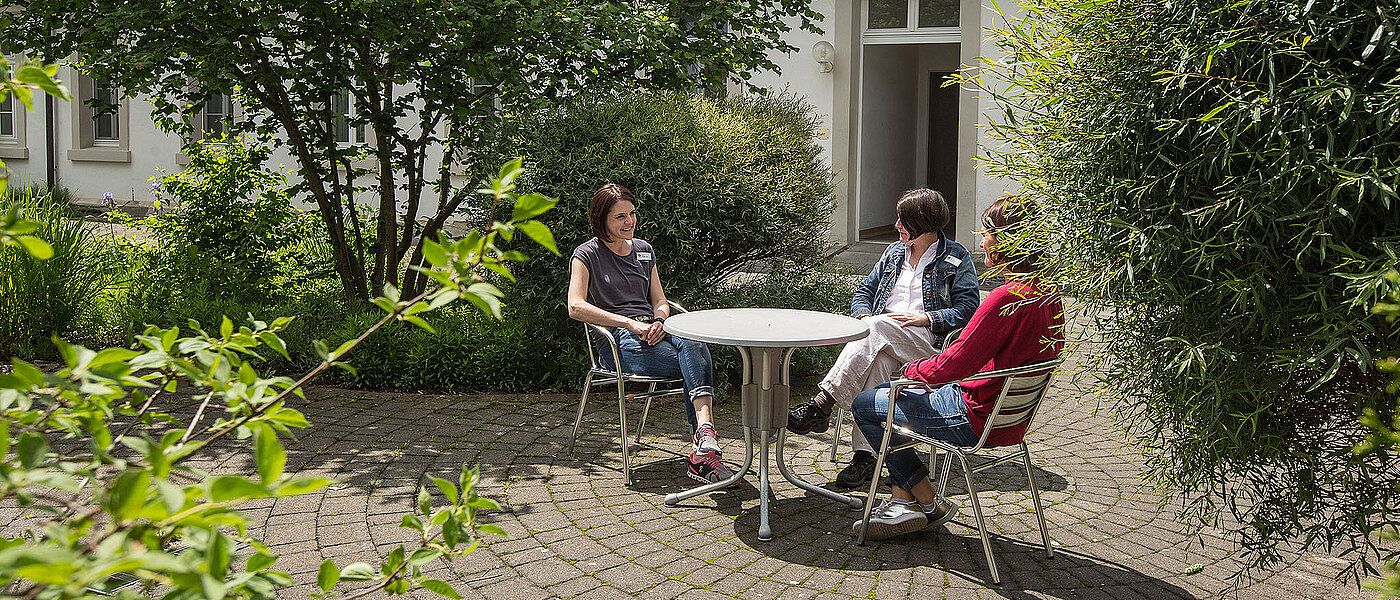 Drei Frauen sitzen im Garten und unterhalten sich