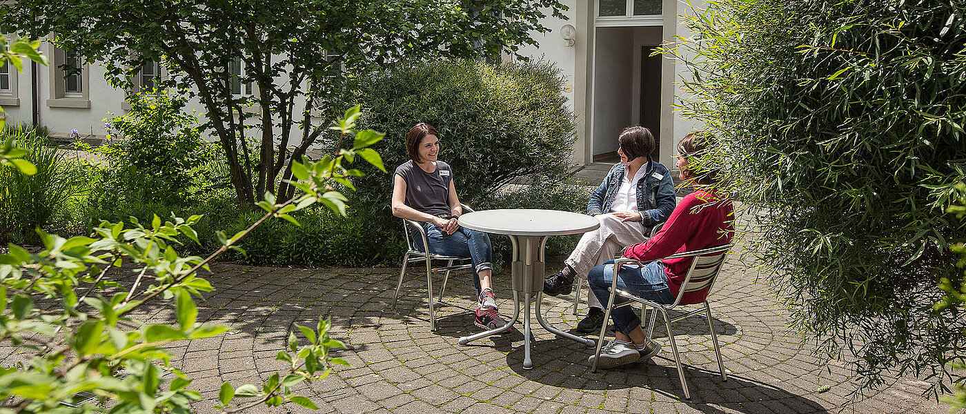 Drei Frauen sitzen im Garten und unterhalten sich