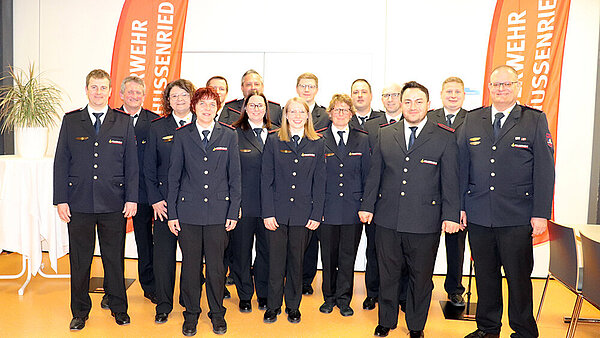 Eine Trupp Feuerwehrleute hat in Uniform Aufstellung genommen.