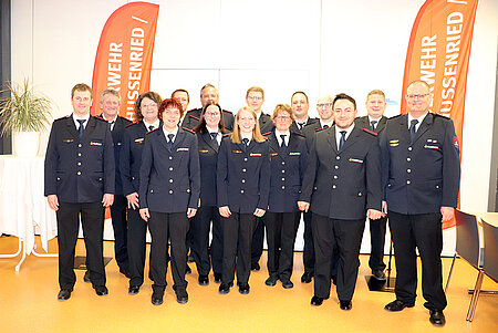 Eine Trupp Feuerwehrleute hat in Uniform Aufstellung genommen.