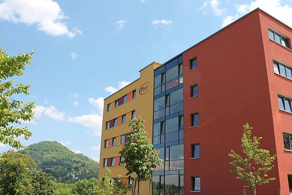 Gelb-rotes Hochhaus mit der Schwäbischen Alb im Hintergrund. 