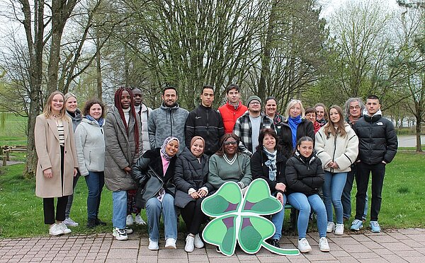 Eine Gruppe an Personen sitzt und steht beisammen und lächelt in die Kamera.