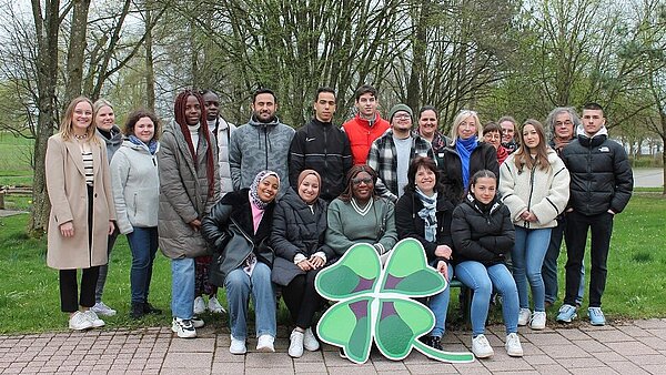 Eine Gruppe an Personen sitzt und steht beisammen und lächelt in die Kamera.