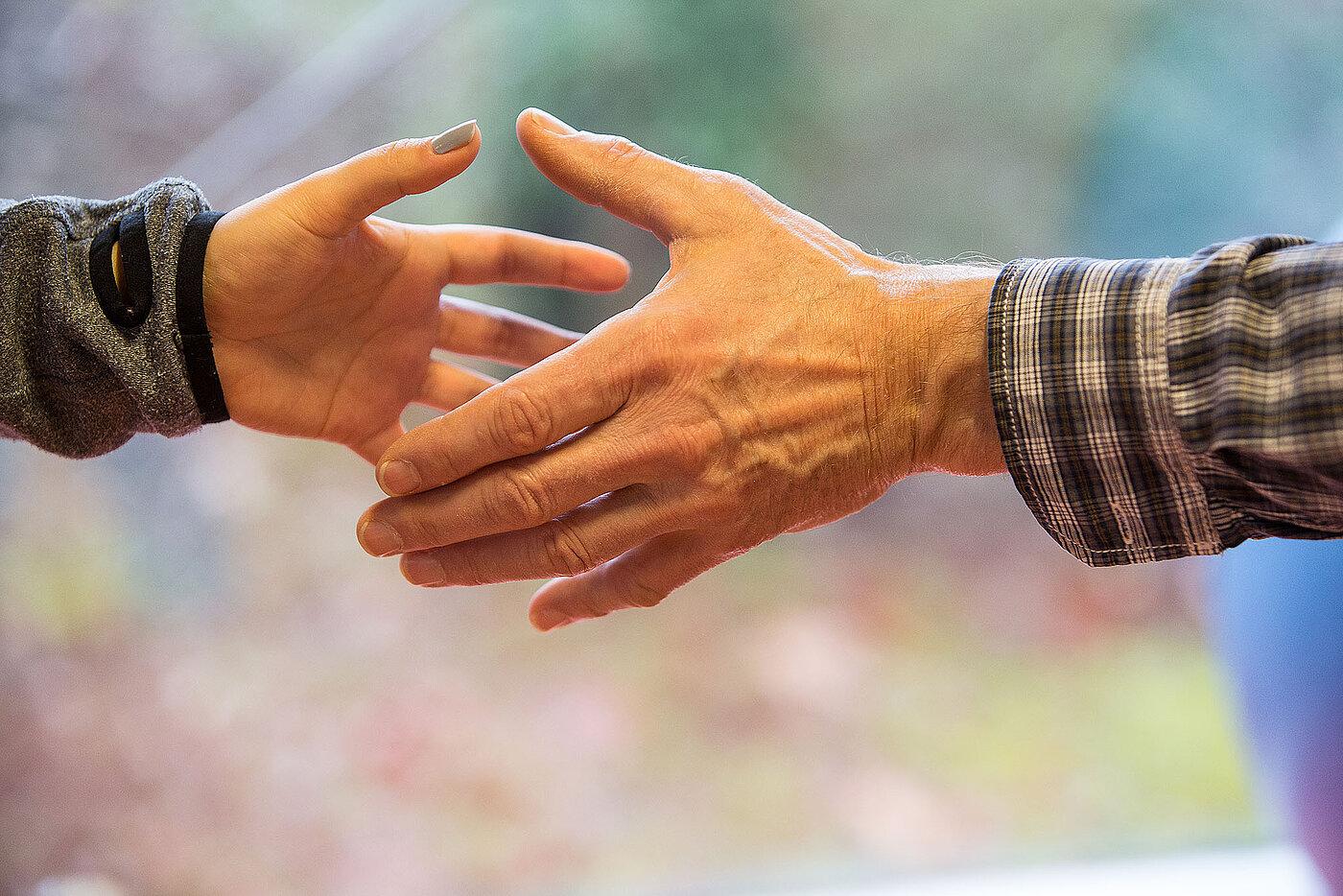 Eine große und eine kleine Hand beim Hände reichen