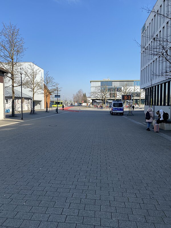 Blick auf die Bushaltespuren, Autos auf den Straßen und Fußgänger am Bahnhofsgelände Ravensburg