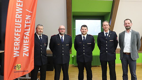 Fünf Herrn stehen nebeneinander, 4 davon tragen Feuerwehruniform.