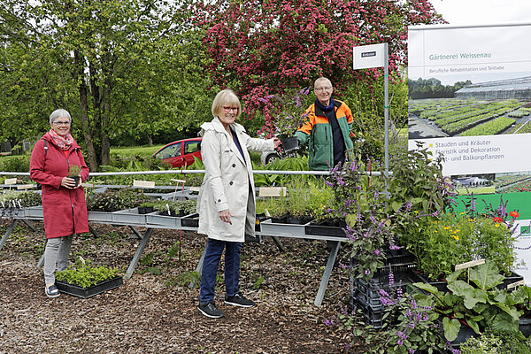 Zwei Frauen und ein Mann im Kräutergarten