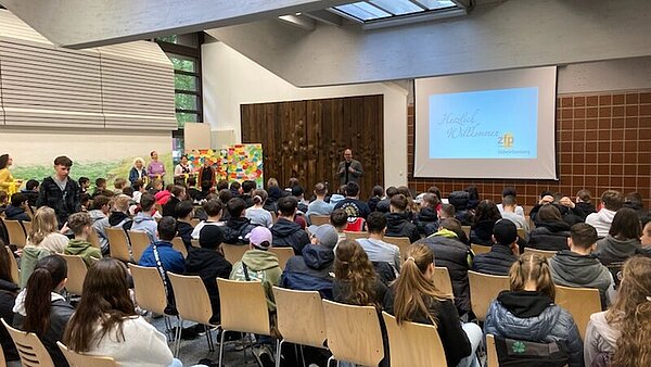 Junge Menschen sitzen in einem Raum und hören dem Redner zu.