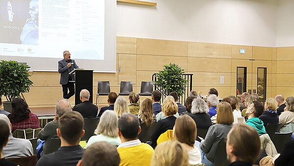 Ein Saal voller interessierter Zuhörer, ein Mann steht am Rednerpult.