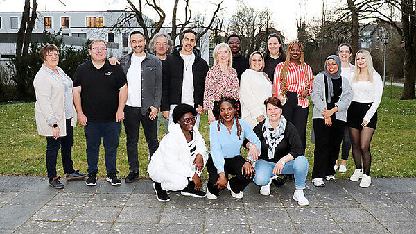 Rund 15 junge Menschen posieren ausgelassen für ein Gruppenbild.