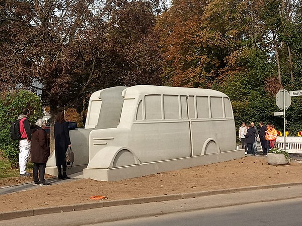 Ein grauer zweiteiliger Bus als Denkmal