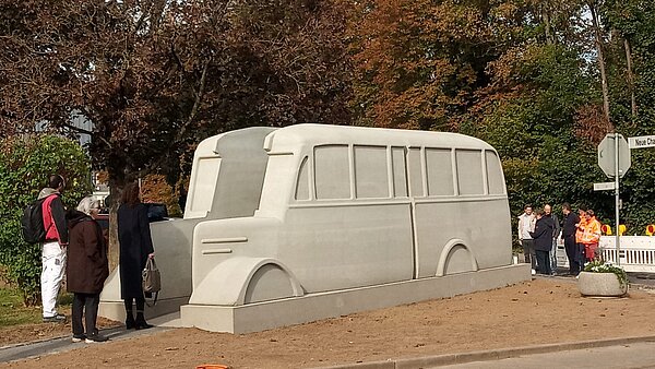 Ein grauer zweiteiliger Bus als Denkmal