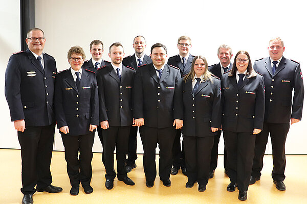 Ein Gruppenbild mit elf Personen in Feuerwehruniform. 