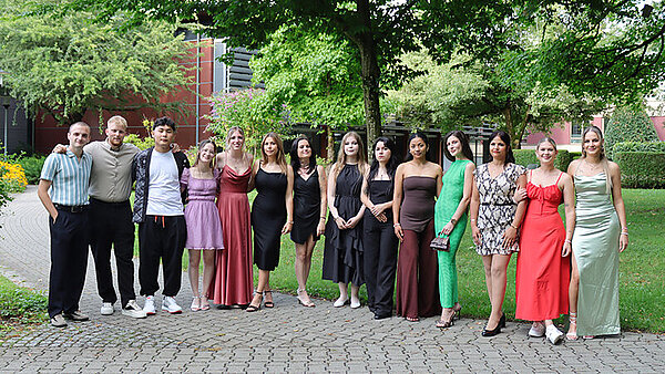 Festlich gekleidete junge Menschen haben sich zum Gruppenbild aufgestellt.