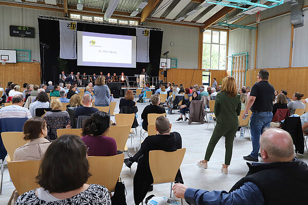 Blick in die gut gefüllte Rentalhalle in Zwiefalten, zu sehen sind zahlreiche Zuhörer und das Podium mit den Referentinnen und Referenten.