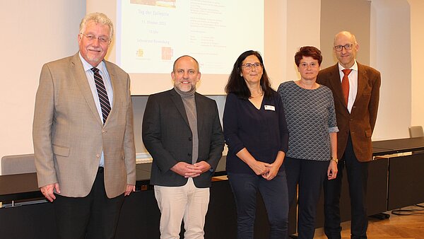 drei Männer und zwei Frauen stehen nebeneinander und schauen freundlich in die Kamera.