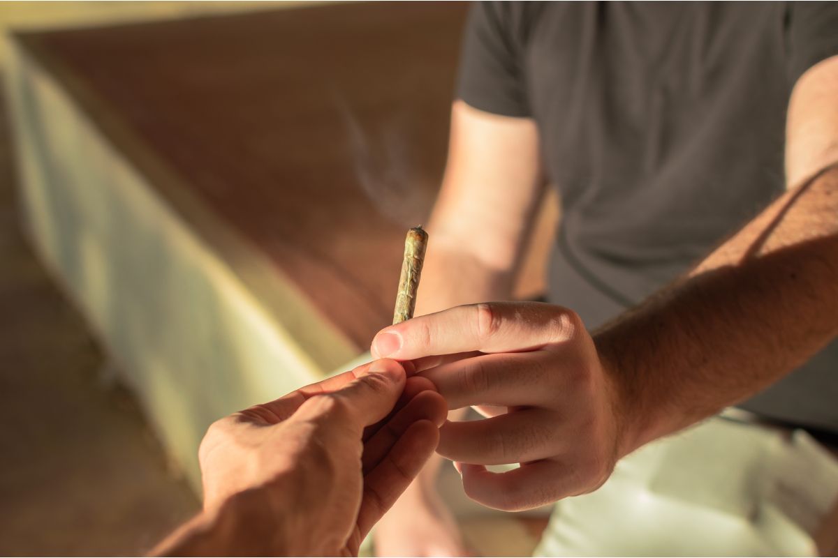 Nahaufnahme von zwei Händen, die sich einen Joint reichen. 